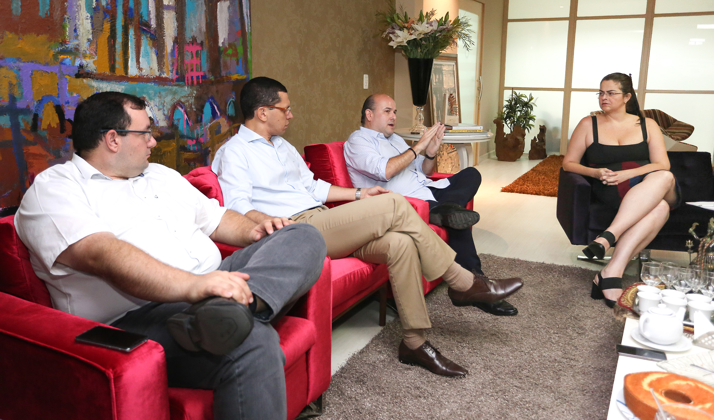 várias pessoas numa sala, sentadas em poltronas, conversando